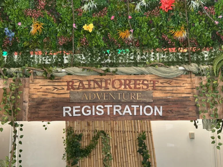 Wooden rainforest-themed sign surrounded by tropical greenery for VBS at Atholton Church, Columbia, MD