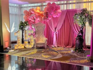 Pink draped backdrop with balloon garland at the quinceañera in BWI, MD