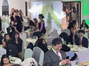 Guests seated at decorated tables with the light green quinceañera cake and butterfly decor at Jimena's quinceañera in Silver Spring, MD