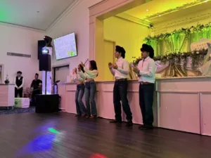 Four young people in cowboy hats clapping on the dance floor at Jimena's quinceañera in Silver Spring, MD