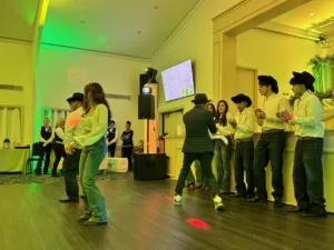 Young men in cowboy hats clapping while a couple dances at Jimena's quinceañera in Silver Spring, MD