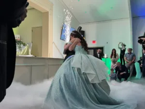 Quinceañera Jimena in a sparkling gown and tiara embracing someone with sparklers and fog at her quinceañera in Silver Spring, MD