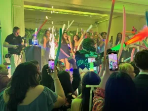 Crowd with colorful foam glow sticks and LED performer with sparklers at Jimena's quinceañera in Silver Spring, MD