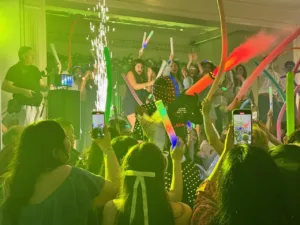 Guests waving colorful foam glow sticks with sparklers and LED performer at Jimena's quinceañera in Silver Spring, MD