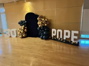 30th birthday marquee letters '30' and 'POPE' with black and gold balloon columns and black arched backdrop on wood floor, Fairfax VA
