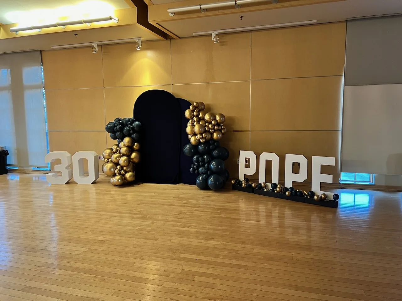 30th birthday party setup with large '30' and 'POPE' marquee letters, black and gold balloon garlands, and black arched backdrop, Fairfax VA
